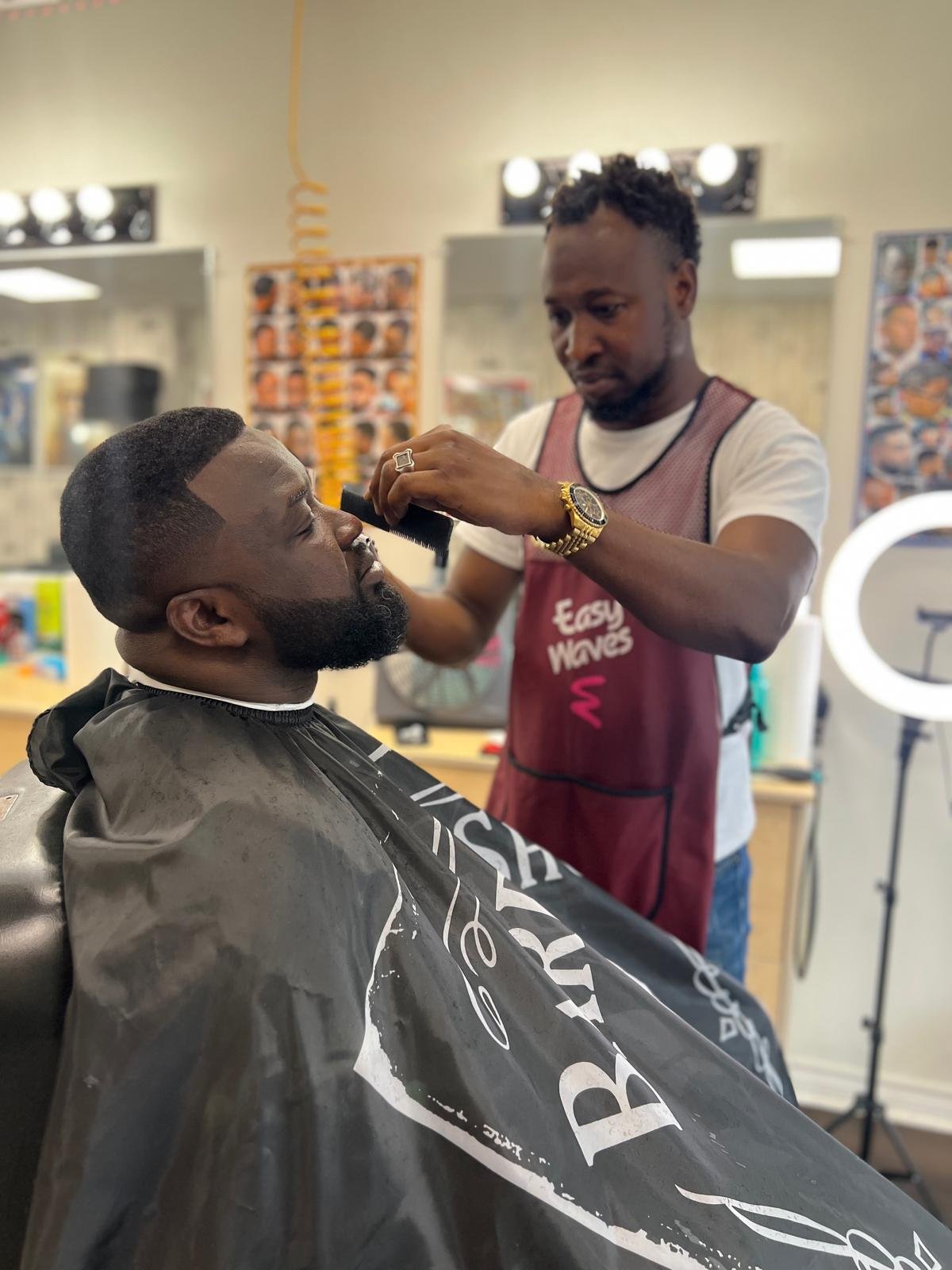 Barber detailing a client's beard and line-up