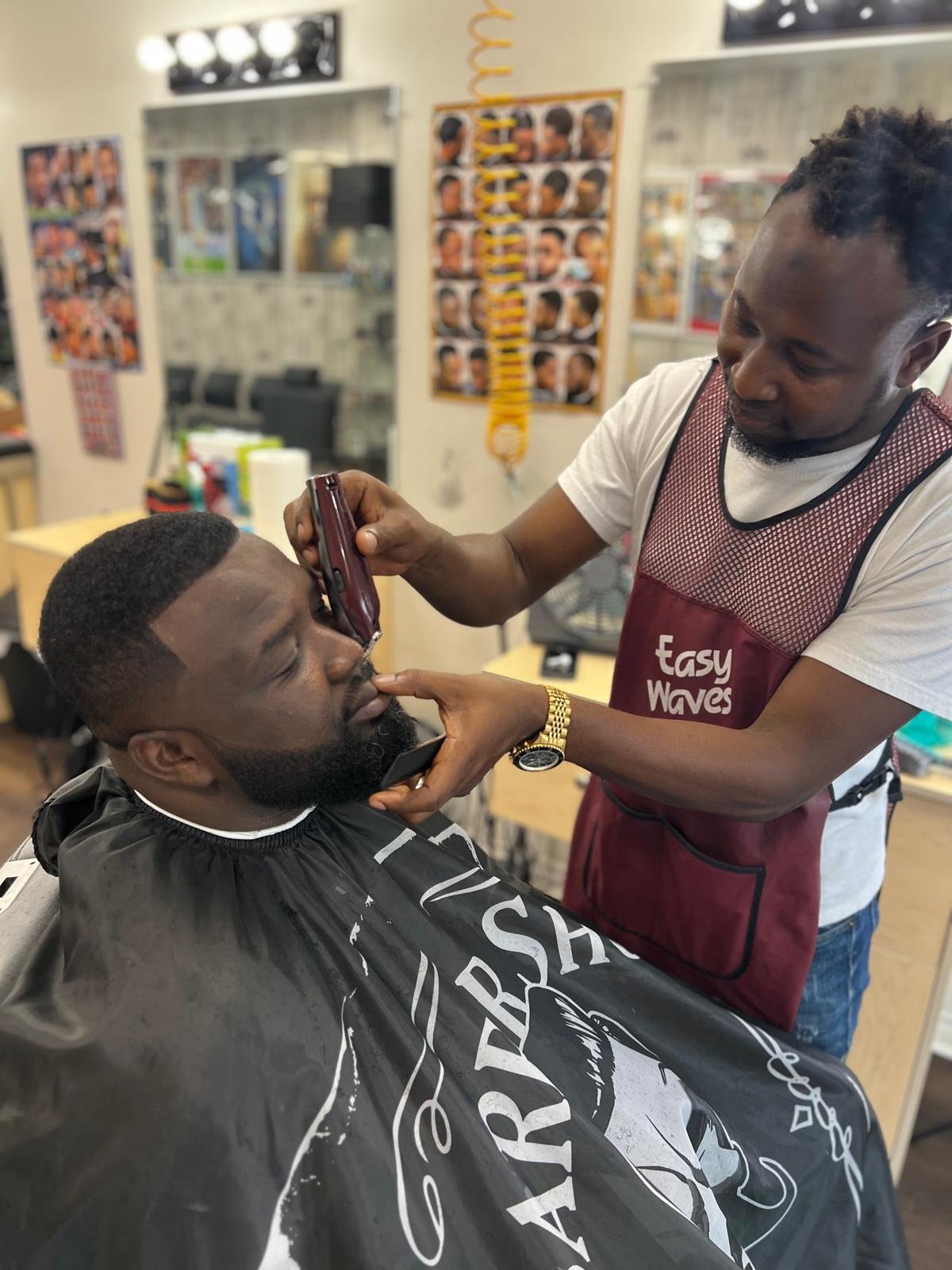 Barber shaping a client's beard with clippers